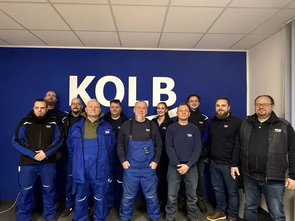 Kolb-Team am Standort Landsberg vor dem Kolb-Logo